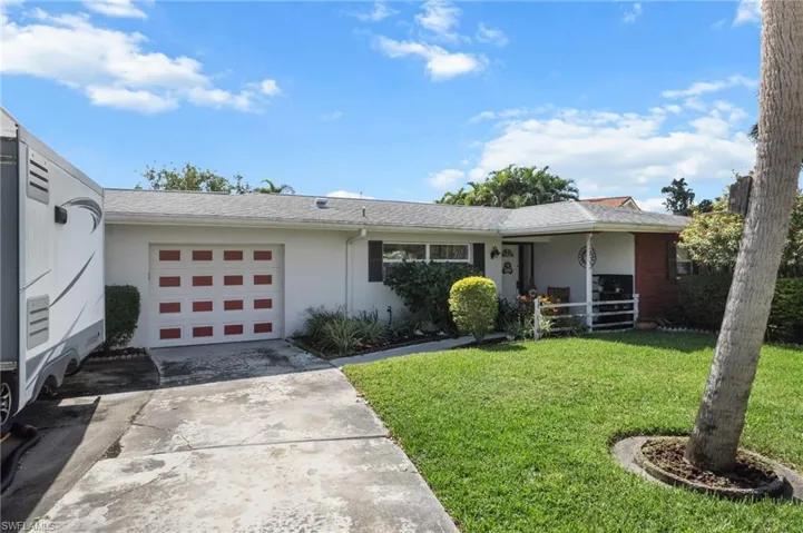 Single story home with a front lawn, driveway, an attached garage, and roof with shingles