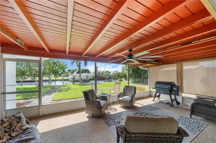 Sunroom with beam ceiling, ceiling fan, a water view, and outdoor lounge area