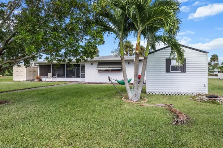Single story home with a front yard, a sunroom, and a storage unit