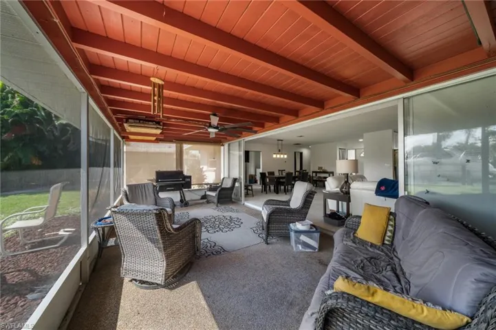 Sunroom / solarium featuring outdoor dining space, ceiling fan, an outdoor living space, and beam ceiling