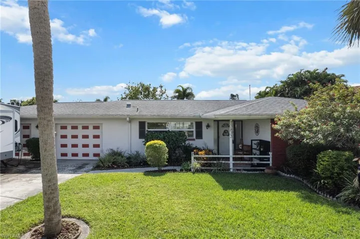 Ranch-style house featuring a front lawn, stucco siding, concrete driveway, a shingled roof, and covered porch
