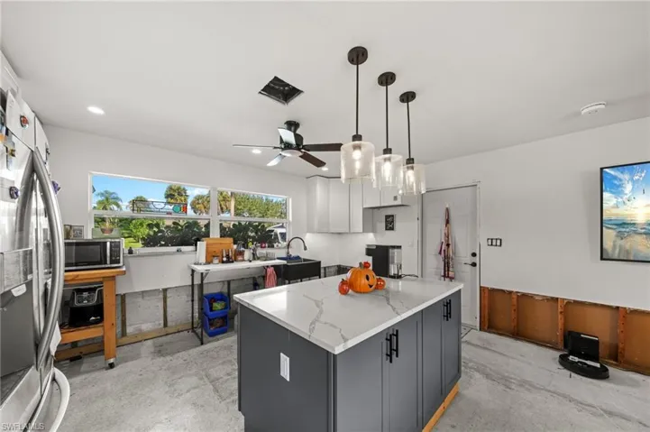 Kitchen featuring pendant lighting, appliances with stainless steel finishes, ceiling fan, a center island, and white cabinetry