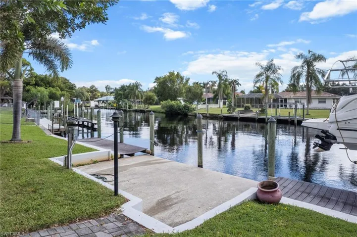 Dock area featuring a water view, a lawn, and a residential view