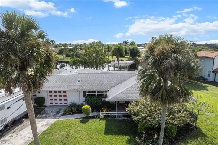View of front of home with a front lawn, concrete driveway, a garage, and roof with shingles