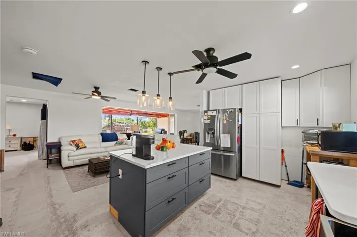 Kitchen with recessed lighting, stainless steel fridge with ice dispenser, pendant lighting, open floor plan, and white cabinetry