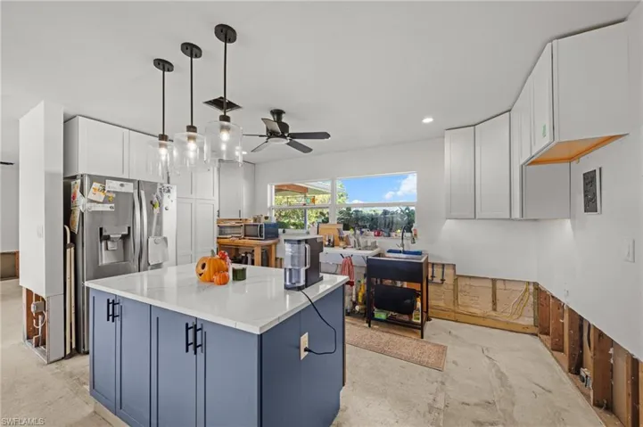 Kitchen featuring white cabinetry, blue cabinets, a kitchen island, pendant lighting, and ceiling fan