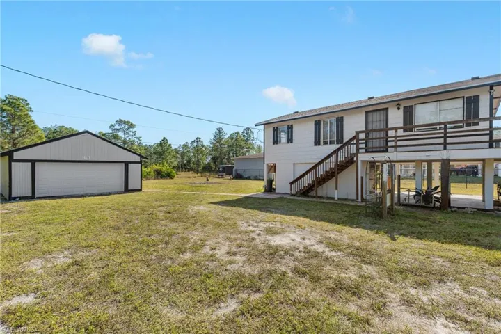 View of yard featuring a garage, an outdoor structure, and a deck
