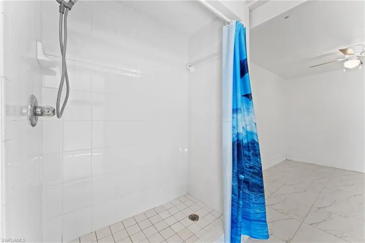 Bathroom featuring curtained shower and ceiling fan