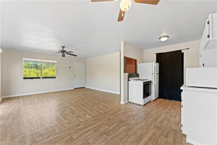 Kitchen featuring white cabinetry, ceiling fan, white appliances, and light wood-type flooring