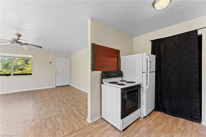 Kitchen with ceiling fan, white appliances, a textured ceiling, and light hardwood / wood-style flooring