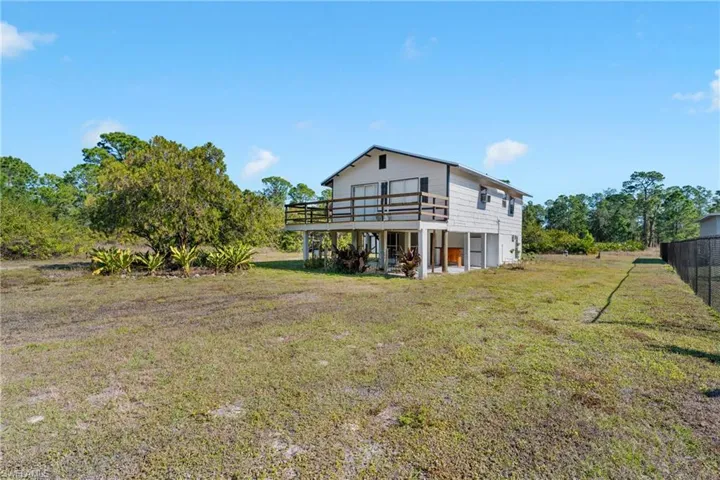 Rear view of house featuring a lawn and a wooden deck