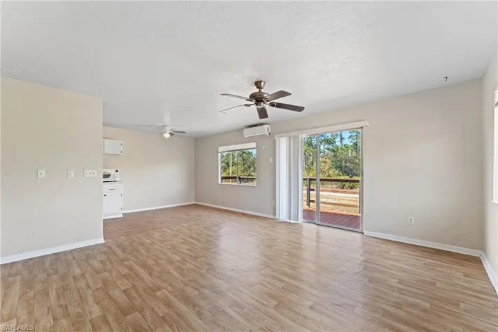 Empty room featuring a wall unit AC, ceiling fan, light hardwood / wood-style floors, and a textured ceiling