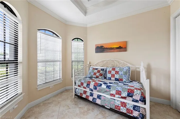 Bay window featuring three arched top windows with horizontal blinds, tray ceiling, tile flooring, and neutral wall paint