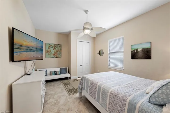 Bedroom featuring neutral wall tones, tile flooring, a window with horizontal blinds, a ceiling fan with integrated lighting, and a white bi-fold closet door