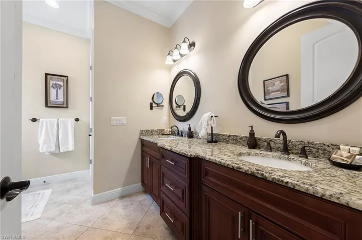 Dual vanity with granite countertops, undermount sinks, and dark wood-finish cabinetry