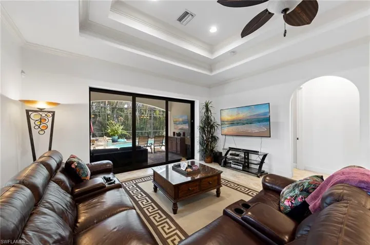 Living area featuring a tray ceiling, recessed lighting, and a ceiling fan