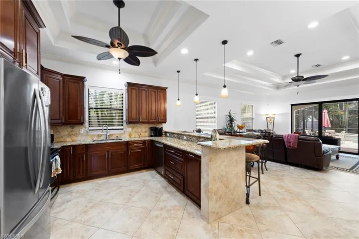Spacious kitchen featuring rich wood cabinetry, stainless steel appliances, and a breakfast bar with stone countertops