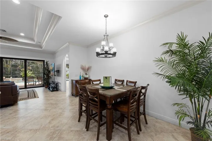 Open-concept dining area featuring tile flooring, crown molding, and a chandelier with glass shades