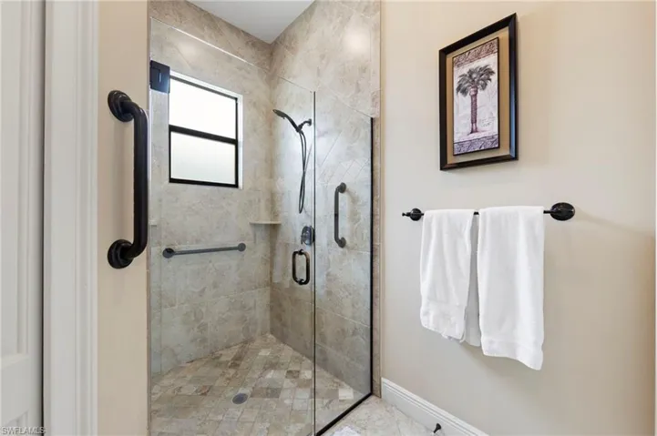 Glass-enclosed shower featuring large format tile walls and a mosaic tile floor