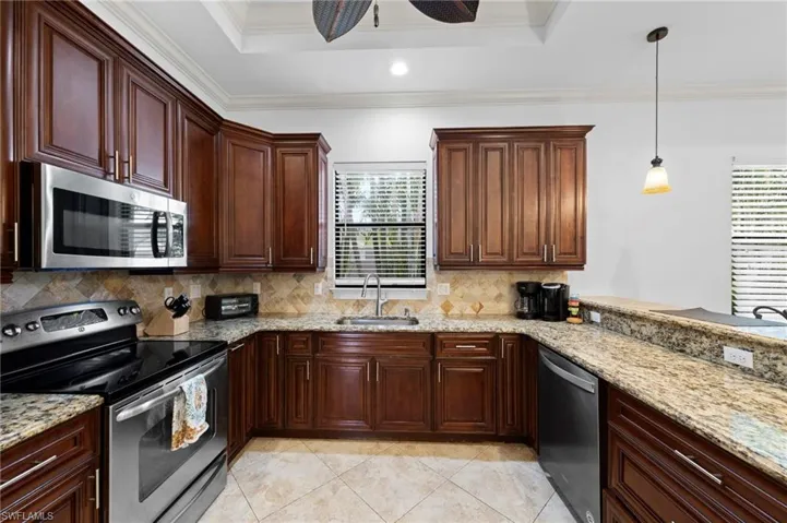 Kitchen featuring wood cabinetry, stainless steel appliances, granite countertops, and a tile backsplash