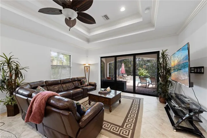 Spacious living area featuring a tray ceiling with a ceiling fan, recessed lighting, and large format tile flooring