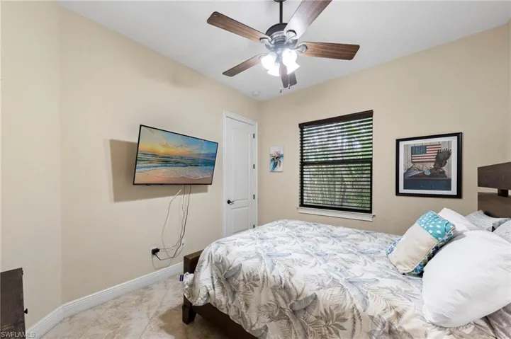 Bedroom featuring neutral wall color, ceiling fan with integrated lighting, a window with horizontal blinds, and tile flooring