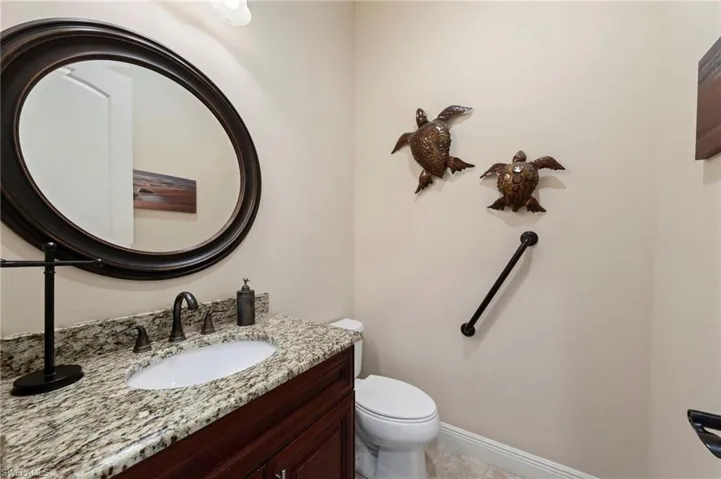 Bathroom vanity featuring a granite countertop, oval undermount sink, and a dark bronze widespread faucet