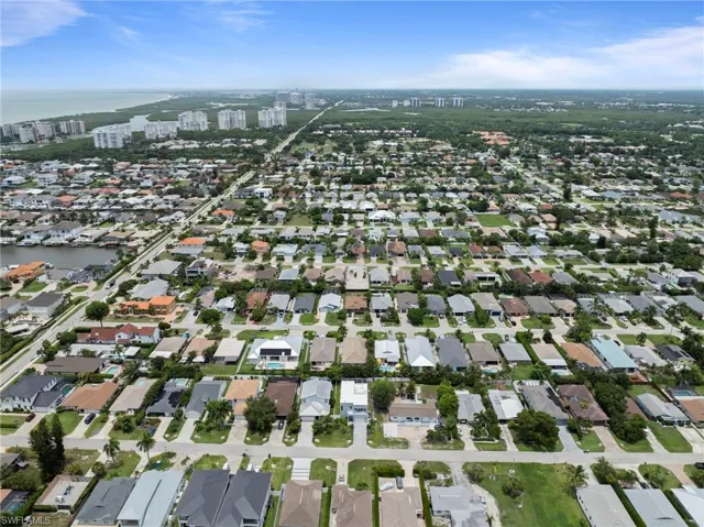 Aerial perspective showcasing a residential area with a prominent waterway, numerous single-story homes, and a distant coastline