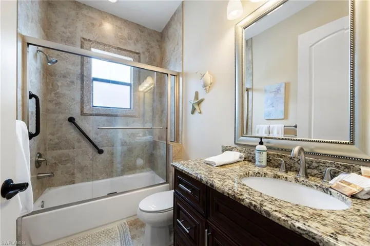 Bathroom featuring a shower-tub combination with glass enclosure, tiled surround, and integrated window