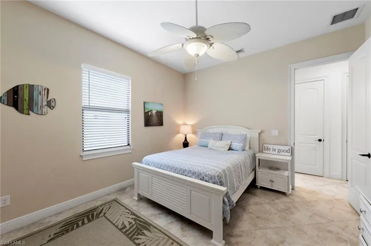Bedroom featuring a ceiling fan with integrated lighting, a window with horizontal blinds, and neutral-toned walls