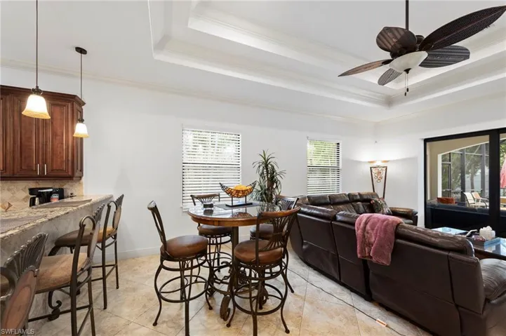 Open-concept living space featuring tray ceilings, ceiling fan, and tile flooring