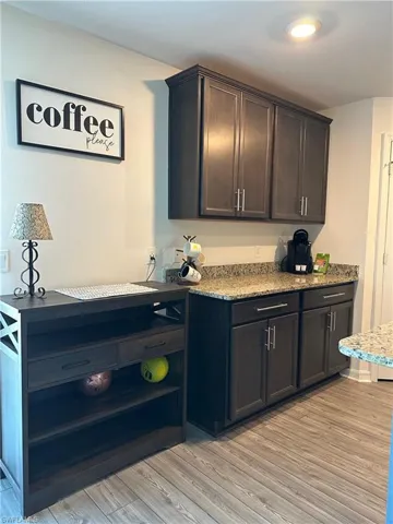 Kitchen with light stone counters, light hardwood / wood-style floors, and dark brown cabinetry