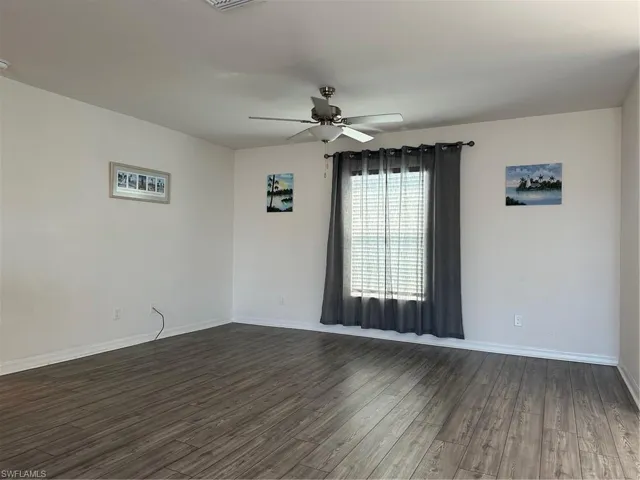Unfurnished room featuring ceiling fan and dark hardwood / wood-style floors
