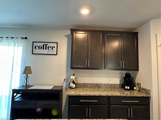 Kitchen featuring light stone counters and dark brown cabinetry