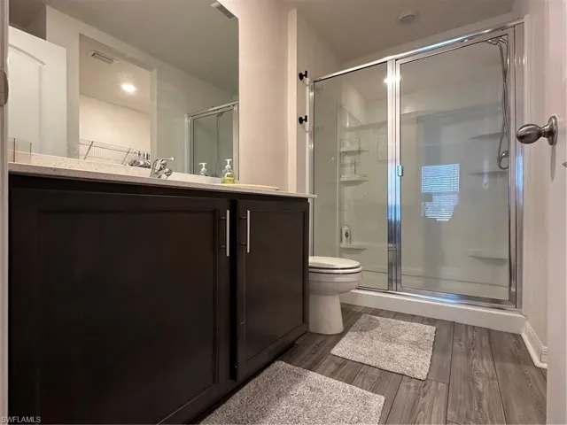 Bathroom featuring walk in shower, toilet, vanity, and hardwood / wood-style flooring