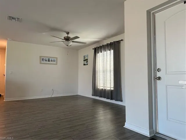 Empty room with ceiling fan and dark hardwood / wood-style flooring