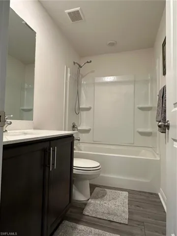 Full bathroom featuring toilet, vanity, hardwood / wood-style flooring, and bathing tub / shower combination