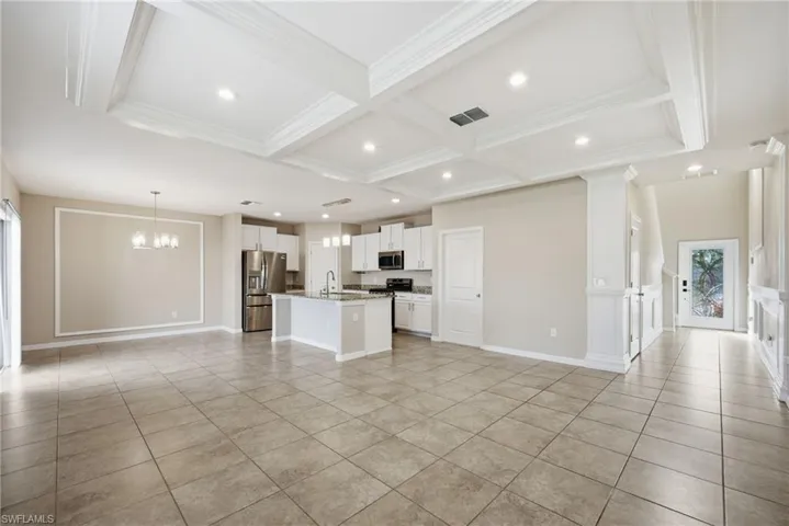 Kitchen with open floor plan, white cabinets, an island with sink, stainless steel appliances, and suspended lighting