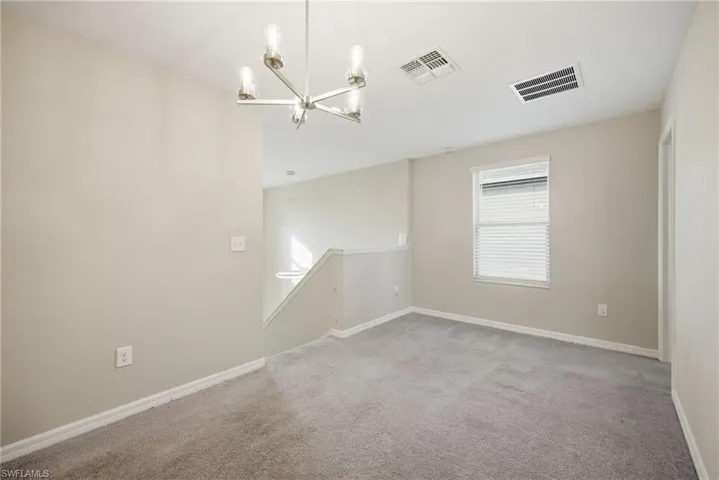 Spare room with light colored carpet and suspended lighting