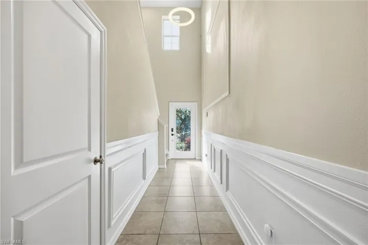 Hallway with wainscoting, a decorative wall, and a high ceiling