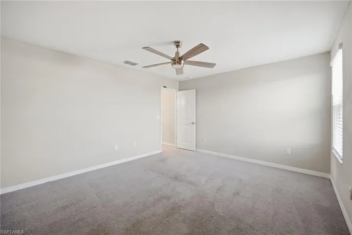 Carpeted spare room with baseboards and ceiling fan