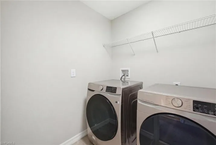 Laundry area with washing machine and clothes dryer and baseboards