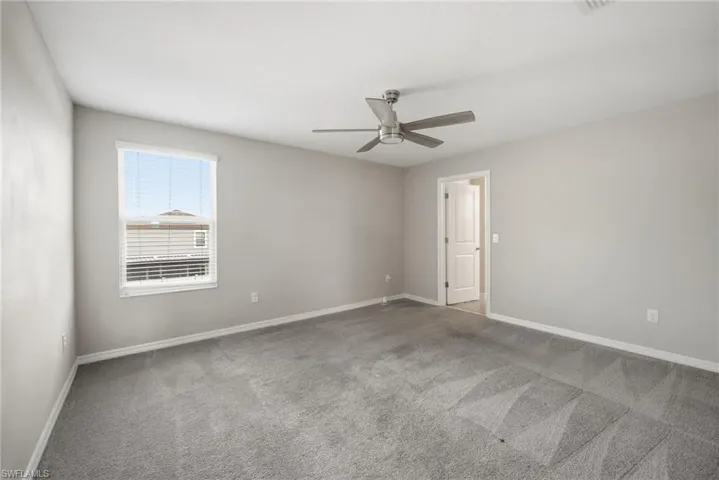 Empty room featuring light colored carpet and a ceiling fan
