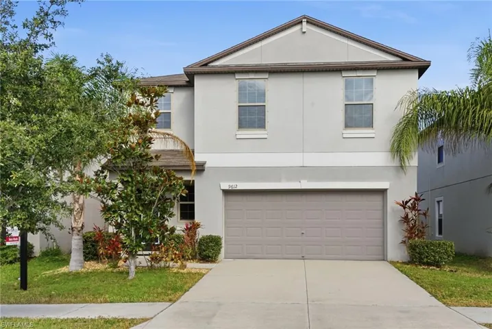 Traditional home with stucco siding, concrete driveway, an attached garage, and a front yard