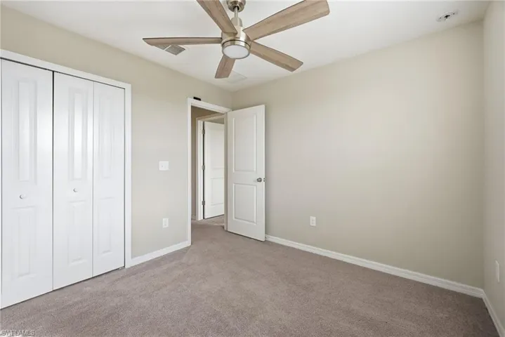 Unfurnished bedroom featuring carpet floors, a closet, and a ceiling fan