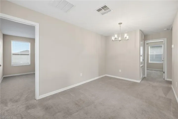Empty room with light carpet and suspended lighting