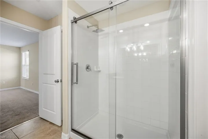 Bathroom featuring a shower stall, tile patterned floors, and carpet