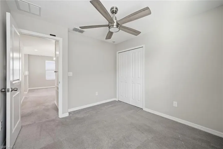 Unfurnished bedroom featuring carpet, a closet, and a ceiling fan