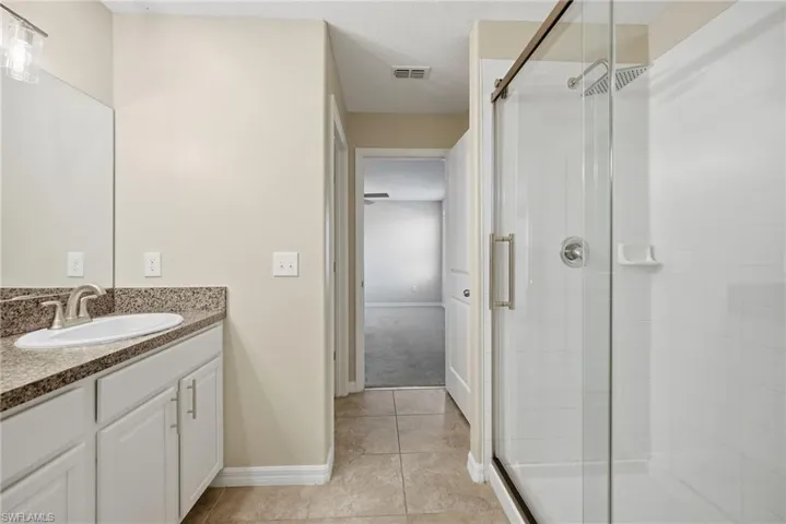 Full bathroom with vanity, a stall shower, and light tile patterned flooring