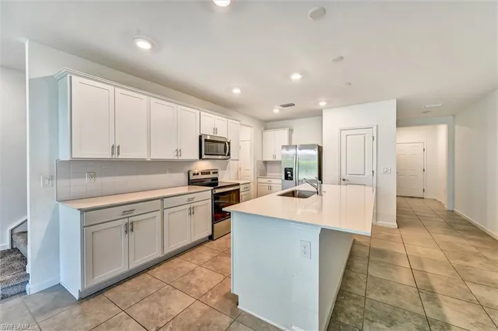 Spacious open-concept kitchen with white cabinetry, quartz countertops, stainless steel appliances, and abundant natural light, ideal for home chefs and families alike.